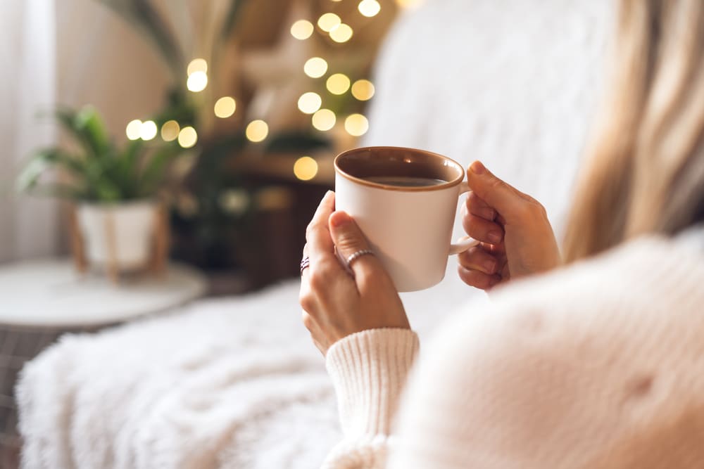 Woman's,Hands,In,Sweater,Holding,Cup,Of,Hot,Drink,Coffee
