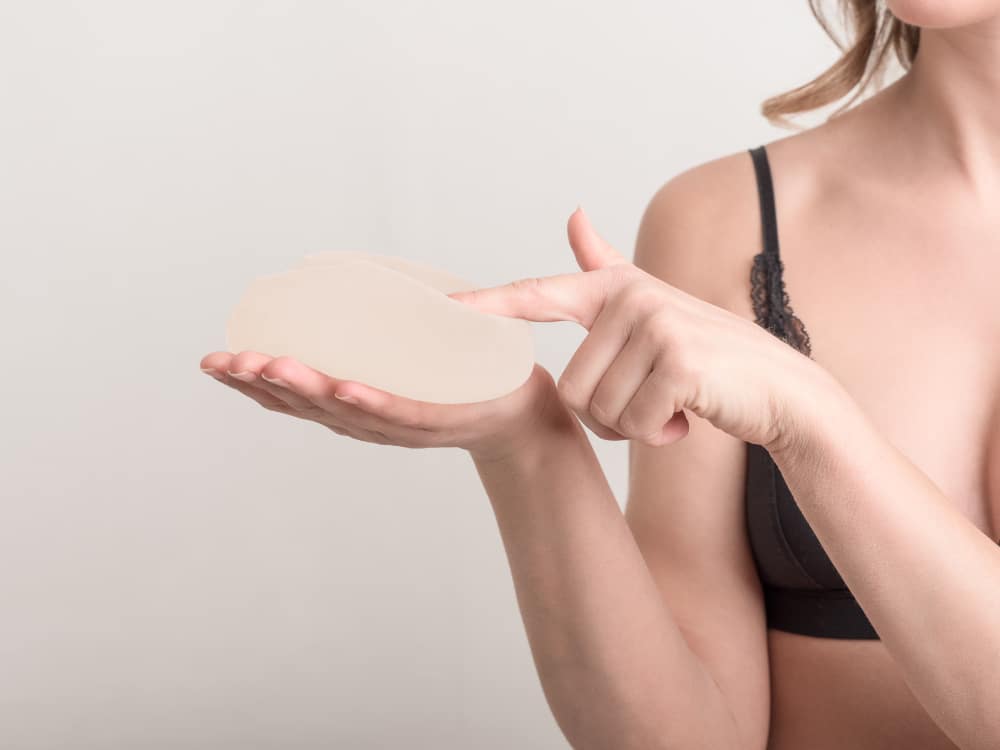 A close-up shot of a woman holding a breast implant in her hand