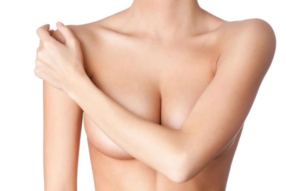 A close-up shot of a woman covering her breasts with her arm