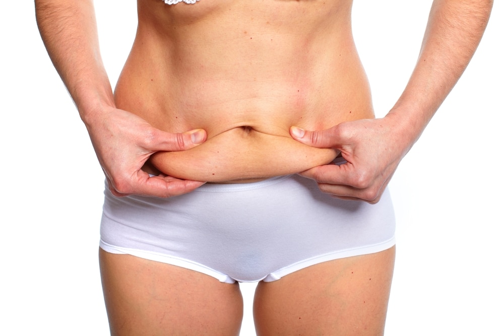 A cropped shot of a woman pulling on loose skin after weight loss